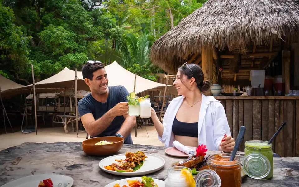 A couple raising a toast under a beach palapa